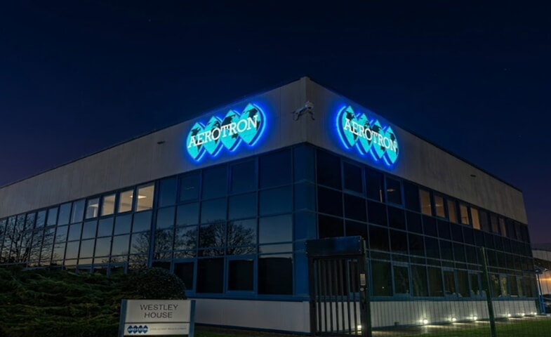 An image of the Aerotron exterior building signage lit up at night.